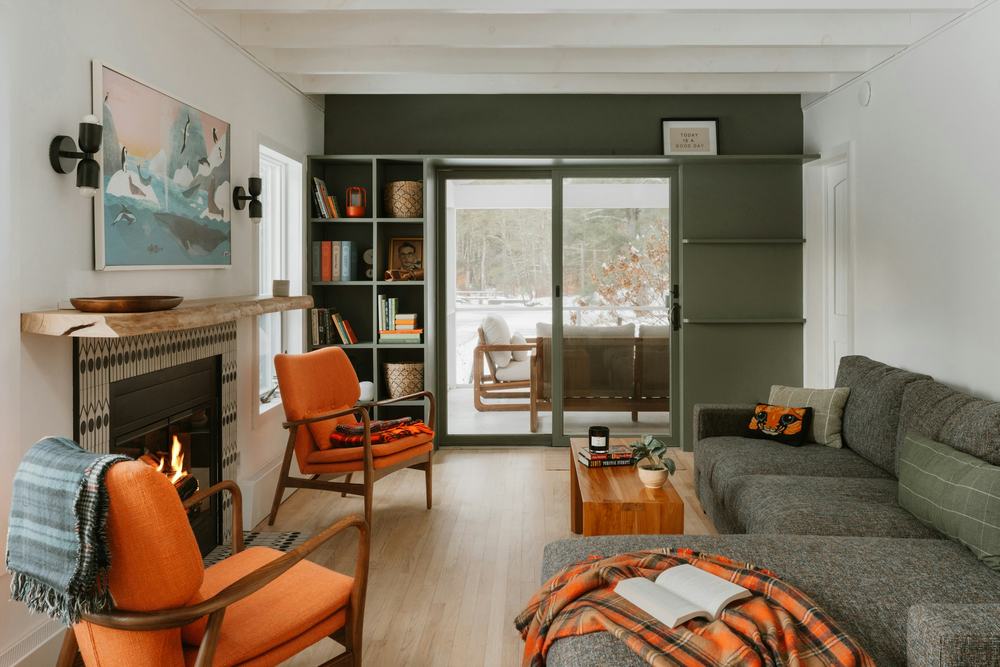 Warm living room with orange armchairs, a lit fireplace and a grey sofa